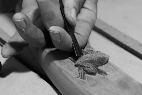 hands carving a frog